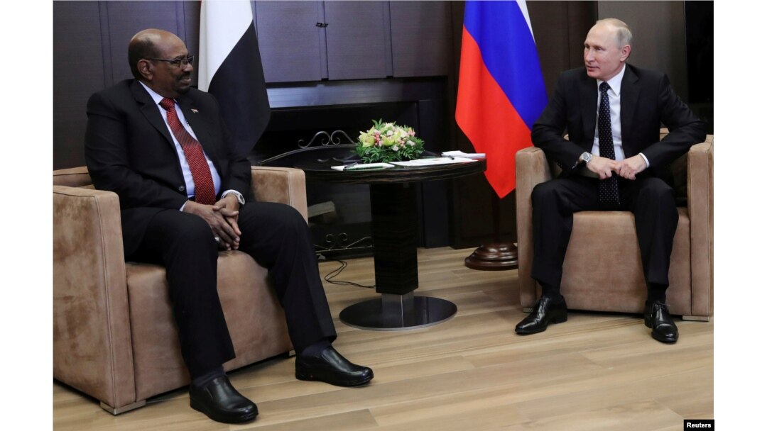 FILE - Russian President Vladimir Putin talks with Sudanese President Omar al-Bashir during their meeting in the Black Sea resort of Sochi, Russia, Nov. 23, 2017.