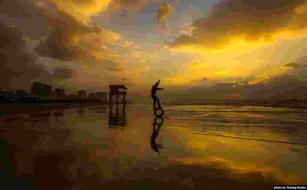 A Palestinian youth attempts to balance on a tire on the beach at sunset in Gaza City.