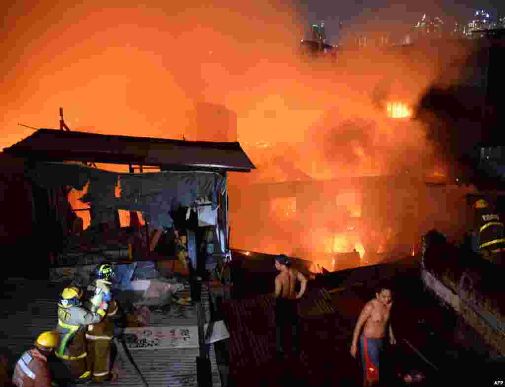 Firefighters and residents try to put out a fire that swept over several houses in an informal settlers area in Manila, Philippines.