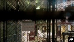 ນັກໂທດຄົນນຶ່ງຍ່າງຢູ່ໃນຄຸກທີ່ອ່າວ Guantanamo ຖານທັບເຮືອສະຫະລັດ ໃນ Cuba.