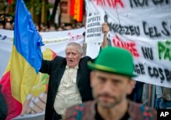 Romania Canada Gold Mine Protest: FILE -A man holding a banner that reads "Stop the Rosia Montana siege" shouts during a protest in Bucharest, Romania, in this Sunday, Sept. 22, 2013 file photo.