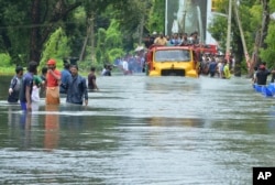 FILE - A truck carries people past a flooded road in Thrissur, in the southern Indian state of Kerala, Aug. 18, 2018.