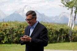 FILE - Federal Reserve Vice Chair Richard Clarida checks his phone during the three-day "Challenges for Monetary Policy" conference in Jackson Hole, Wyo., Aug. 23, 2019.