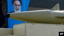 A missile is carried on a truck in front of a portrait of the late Iranian revolutionary founder Ayatollah Khomeini during an annual armed forces parade, just outside Tehran, Iran, Sept. 21, 2024.