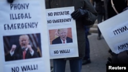 Protesters hold signs during a demonstration against U.S. President Donald Trump on Presidents' Day in Union Square, New York, U.S., February 18, 2019. 