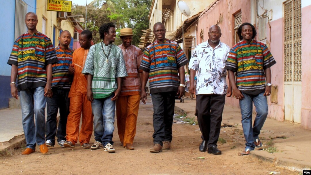 The eight members of Super Mama Djombo, including founder Ze Manel Fortes and composer Atchutchi, walk through the streets of Bissau's old town, Guinea-Bissau, May 2, 2012. (K. Thomas/VOA)