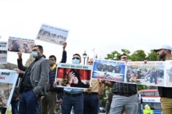 Demonstrators, including former interpreters for the British Army in Afghanistan, hold placards as they protest opposite the Houses of Parliament in London, Aug. 18, 2021.