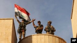 Fuerzas especiales iraquíes celebran con la bandera de Irak en alto por la recuperación de Bartella, en las afueras de Mosul.