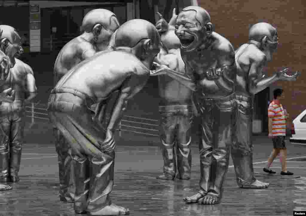 A man walks past a group of art works by Chinese artist Yue Minjun on display outside the Today Art Museum in Beijing.