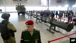FILE - Russian military officers stand by as the 9M729, center, its launcher, left, and the 9M728, right, land-based cruise missiles are displayed in Kubinka outside Moscow, Russia, Jan. 23, 2019. 