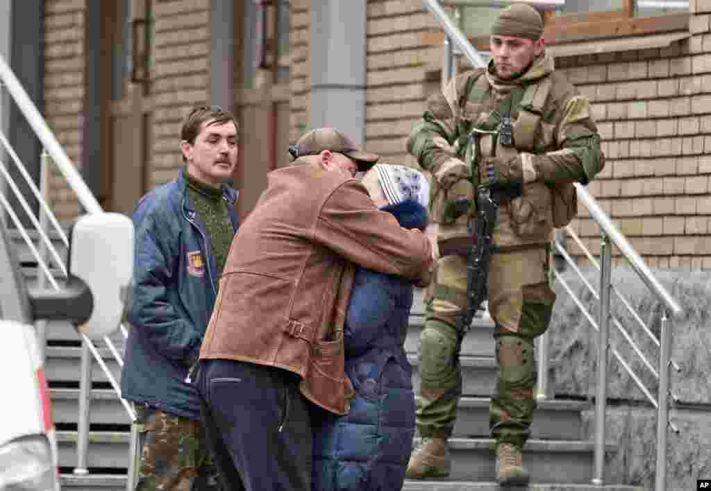 People comfort each other as they wait to hear news about the coal miners after an explosion at the Zasyadko mine while pro-Russian rebels stand nearby, Donetsk, March 4, 2015.