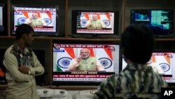 People watch Indian Prime Minister Narendra Modi addressing the nation, on television in Hyderabad, India, Saturday, Dec. 31, 2016. 