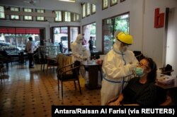 Petugas kesehatan mengambil sampel antigen cepat dari pengunjung di tengah pandemi COVID-19 di Bandung, Jawa Barat, 30 Desember 2020. (Foto: Antara/Raisan Al Farisi via REUTERS)