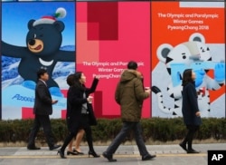 People pass by posters showing the 2018 Pyeongchang Winter Olympic mascots in Seoul, South Korea, Jan. 17, 2018.