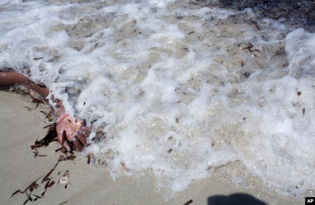 FILE - The arm of a dead migrant is seen at the waterfront of Zuwara, about 105 kilometers (65 miles) west of Tripoli, Libya, Aug. 28, 2015 in this image by photographer and video journalist Mohamed Ben Khalifa, who was killed in Libya on Jan. 19, 2019.