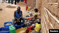 FILE - A Ugandan man cleans his clothes at the Makerere Kivulu slums in Kampala.