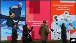 People pass by posters showing the 2018 Pyeongchang Winter Olympic mascots in Seoul, South Korea, Jan. 17, 2018.