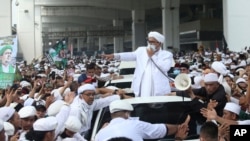 File - Indonesian Islamic cleric and the leader of Islamic Defenders Front Rizieq Shihab, center, speaks to his followers upon arrival from Saudi Arabia at Soekarno-Hatta International Airport in Tangerang, Indonesia, Nov. 10, 2020. 