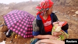 FILE - A woman holds her child as she waits while rescuers search for her husband, a victim of a landslide in Vietnam's northern province of Yen Bai on September 8, 2012.