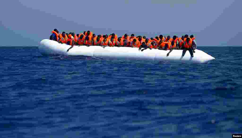 Migrants on a rubber dinghy wait to be rescued by the Migrant Offshore Aid Station (MOAS) ship MV Phoenix, some 20 miles (32 kilometres) off the coast of Libya. Some 118 migrants were rescued from a rubber dinghy off Libya on Monday morning. The Phoenix, manned by personnel from international non-governmental organizations Medecins san Frontiere (MSF) and MOAS, is the first privately funded vessel to operate in the Mediterranean