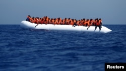 FILE - Migrants on a rubber dinghy wait to be rescued by the Migrant Offshore Aid Station (MOAS) ship MV Phoenix, some 20 miles (32 kilometres) off the coast of Libya. The Responder will patrol the central Mediterranean route between North Africa and Italy.