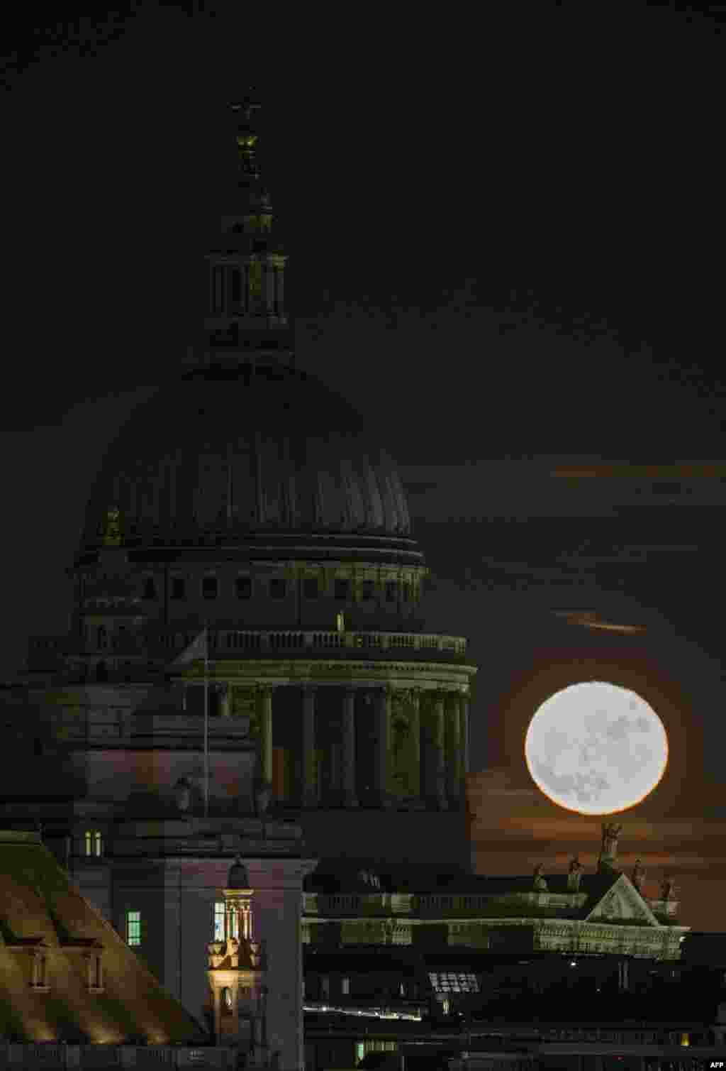 A supermoon rises on the horizon beyond St. Paul&#39;s Cathedral in central London.