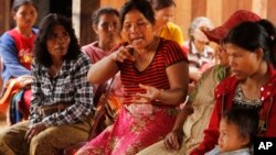 In this Feb. 26, 2015 photo, Kop Let, center, from the indigenous Bunong tribe, speaks during an interview with The Associated Press in Bousra commune, Mondulkiri province, in eastern Cambodia. Kop Let, who is the wife of a village chief, says she struggles to feed her extended 17-member family after the Socfin-KCD plantations swallowed most of the family’s 12 hectares (30 acres). (AP Photo/Heng Sinith)