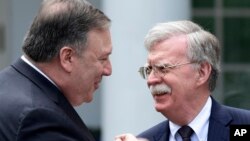 Secretary of State Mike Pompeo, left, and national security adviser John Bolton, right, talk before the start of a news conference in the Rose Garden of the White House in Washington, June 7, 2018.