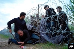 Người tị nạn Syria chui dưới hàng rào kẽm gai vào Hungary, ngày 26/8/2015.