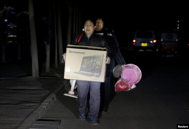 北京的外来务工人员手里提着有限的个人物品被连夜赶出他们在北京通州六环外的住所。(2017年11月23日)