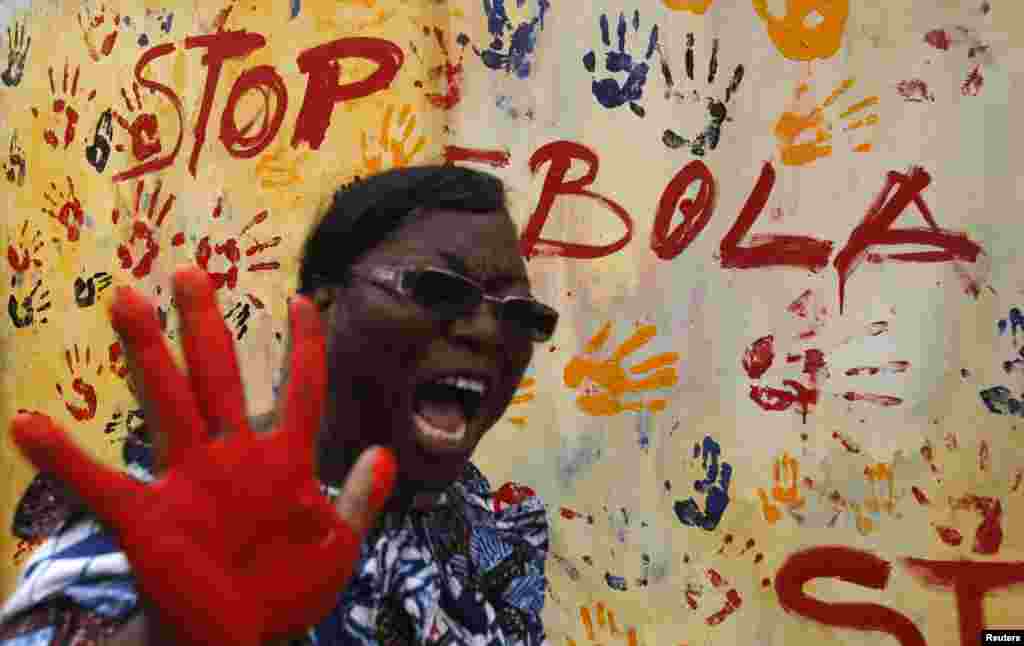 A teacher reacts after adding paint to a canvas following a performance by actors during an awareness campaign against Ebola at Anono school, in Abidjan, Ivory Coast, Sept. 25, 2014. 