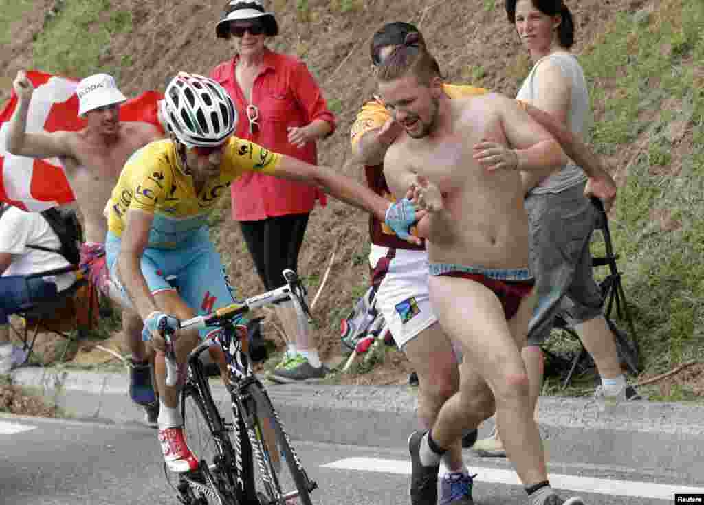 Race leader Astana team rider Vincenzo Nibali of Italy pushes away a spectator as he cycles to win the 145.5km 18th stage of the Tour de France cycling race between Pau and Hautacam.