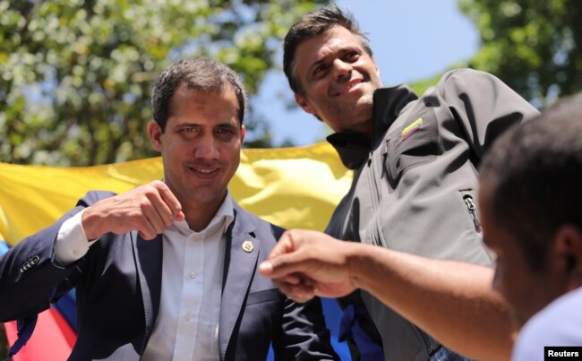 Venezuelan opposition leader Juan Guaido, left, pumps fists with a supporter as fellow opposition leader Leopoldo Lopez looks on in Caracas, April 30, 2019.