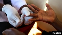 FILE - A doctor draws blood from a man to check for HIV/AIDS at a mobile testing unit in Ndeeba, a suburb in Uganda's capital Kampala. 