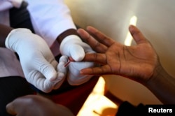 FILE - A doctor draws blood from a man to check for HIV/AIDS at a mobile testing unit in Ndeeba, a suburb in Uganda's capital, Kampala.