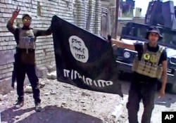 FILE - This image made from Associated Press video shows, Iraqi troops turn the Islamic State flag upside down in Fallujah, Iraq, June 26, 2016.