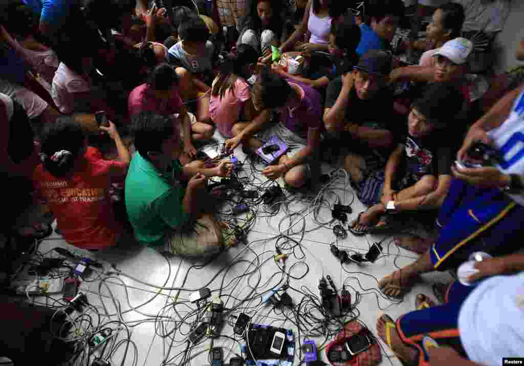 Residents charge their mobile phones with electricity from generators provided for free by the government, during a blackout inside a town hall, after Typhoon Rammasun battered the town of Rosario, Cavite city, south of Manila, July 18, 2014.