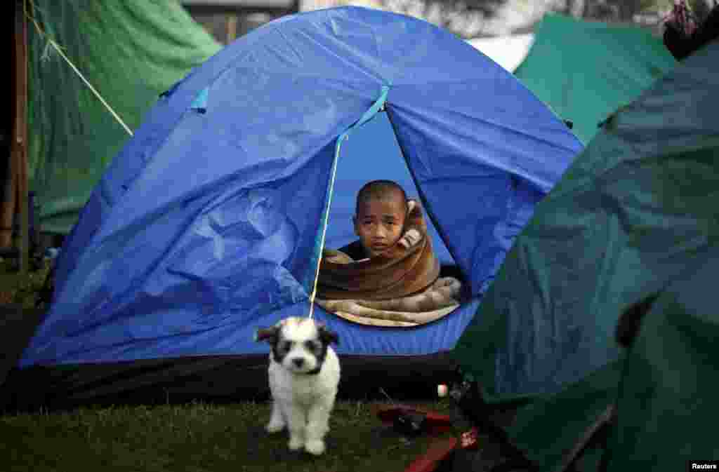 A boy sits inside a tent on open ground, after Saturday&#39;s earthquake in Kathmandu, Nepal.