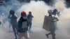 ရန်ကုန်ဆန္ဒပြပွဲအတွင်း မျက်ရည်ယိုဗုံးများ သုံးပြီး ဖြိုခွင်းခံခဲ့ရလို့ အကာကွယ်ယူ ထွက်ပြေးကြတဲ့ ဆန္̔ဒသူတချို့။ (မတ် ၀၁၊ ၂၀၂၁)