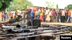 Suspected fighters are paraded before the media by Burundian police near a recovered cache of weapons after clashes in the capital Bujumbura, Burundi, Dec. 12, 2015.