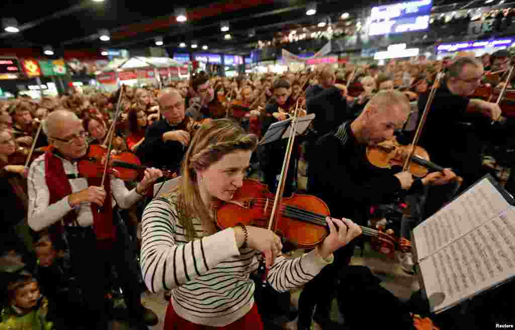 Un grupo de personas cantan y tocan instrumentos durante la presentación de la &quot;Misa de Navidad checa&quot; del compositor checo Jakub Jan Ryba en la estación principal de trenes de Praga, República Checa.