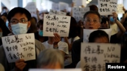 Protesters hold signs following a day of violence over a proposed extradition bill, outside the Legislative Council building in Hong Kong, China, June 13, 2019. 