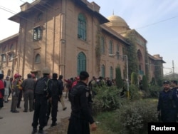 Police and rescue workers stand outside the Directorate of Agriculture Institute in Peshawar, Pakistan, Dec. 1, 2017.