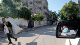 Palestinian woman Naela Abu Jibba, who started a women-only taxi service in the Gaza Strip, is reflected in a mirror as she drives her vehicle at Beach refugee camp in Gaza City on November 17, 2020. (REUTERS/Mohammed Salem)