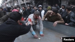 People help a wounded person after a missile hit Aleppo's al-Mashhad district, Syria, January 7, 2013.