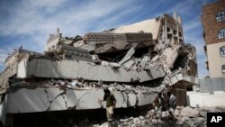 Hommes marchant sur les décombres du QG de la Chambre de commerce et d'industrie , après un raid aérien saoudie à Sanaa , au Yémen , le mardi 5 janvier 2016 .