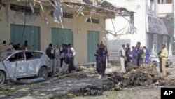 Somali soldiers stand near the wreckage after a car bomb detonated in Mogadishu, Somalia, Dec. 19, 2015. 