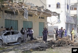 Somali soldiers stand near the wreckage after a car bomb detonated in Mogadishu, Somalia, Dec. 19, 2015.
