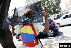 A Venezuelan man wears a backpack with the colours of Venezuelan flag as he sells car accessories at traffic lights in Boa Vista, Brazil, Nov. 18, 2017.