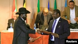 South Sudan's President Salva Kiir (front L) and rebel commander Riek Machar exchange documents after signing a cease-fire agreement during the Inter Governmental Authority on Development (IGAD) Summit, Feb. 1, 2015.